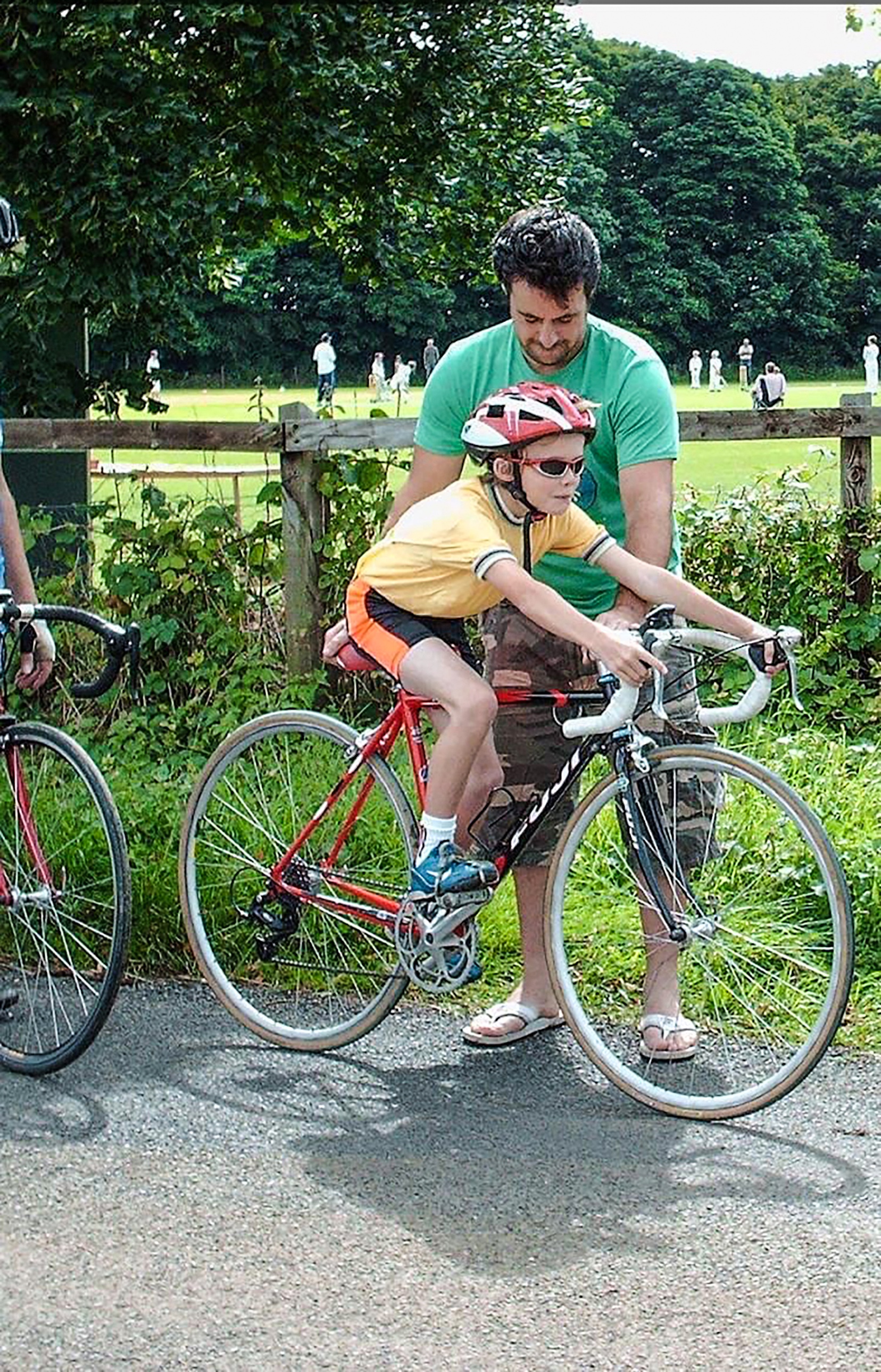 Paul Double as a child riding an oversized bike, being steadied by his dad