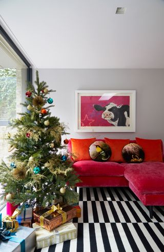 Christmas living room with pink velvet sofa and brightly decorated Christmas tree