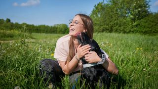 Dog licking owner in a field