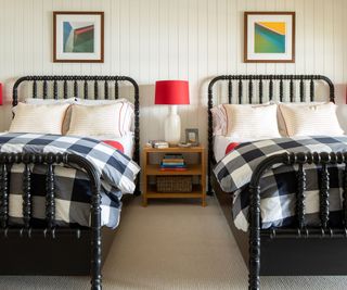 black twin beds with black and white check bedding and white painted paneled walls