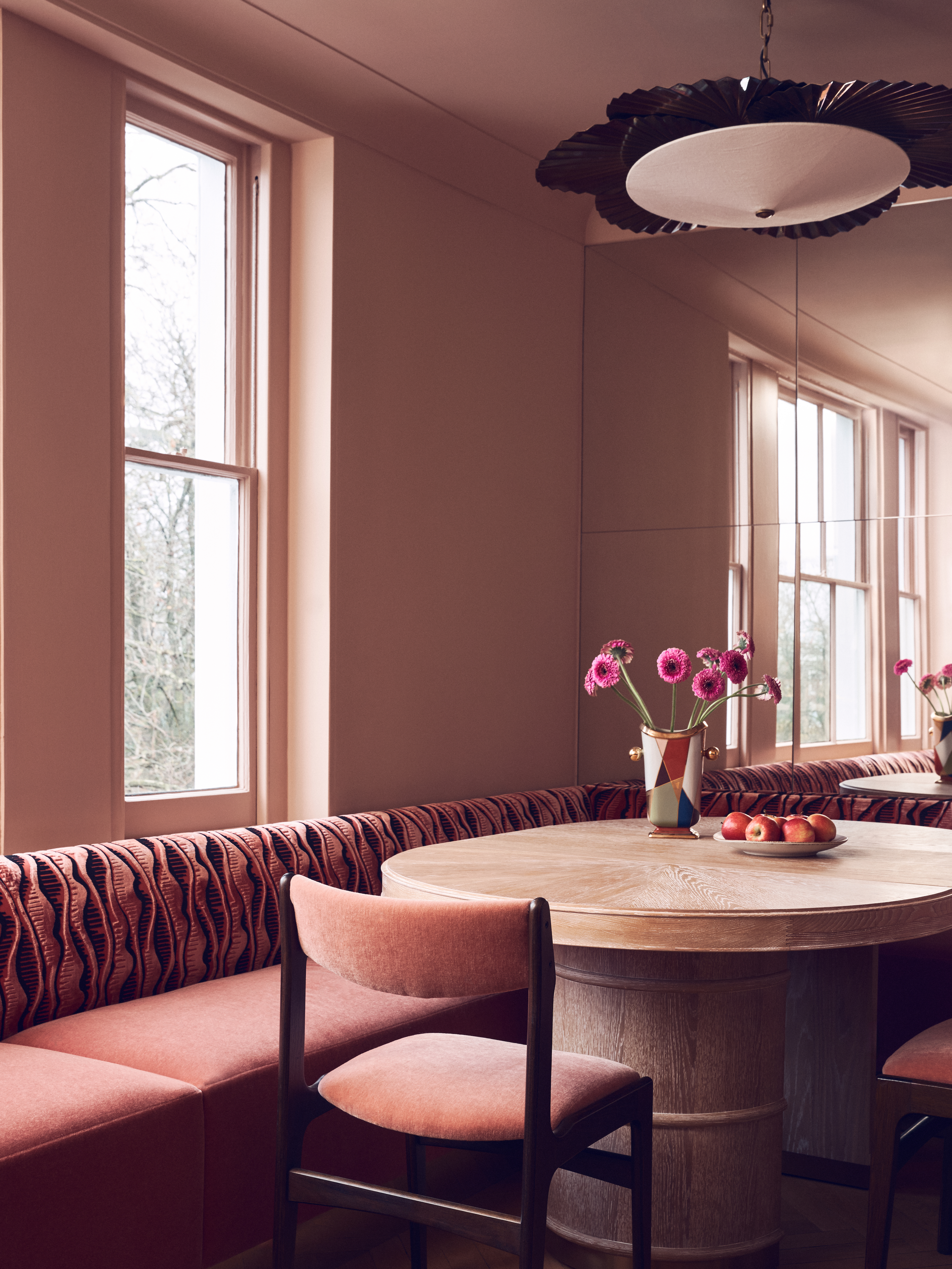 Corner banquette in pink mohair upholstery with coordinating chairs and round wooden table