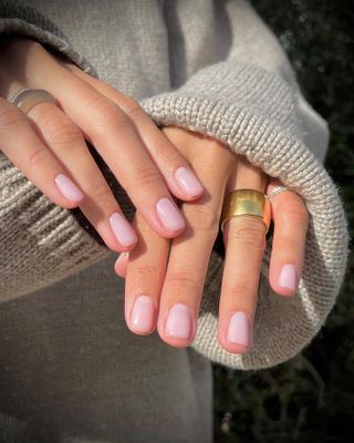 A woman wearing OPI's Love Is In The Bare nail polish