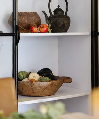 A shelving unit with a wooden brown of small pumpkins
