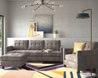 A grey microfiber sofa with statement light fixture and colorful upholstered area rug in living room
