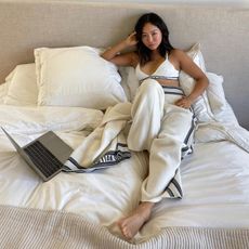 Woman lying in bed next to her laptop