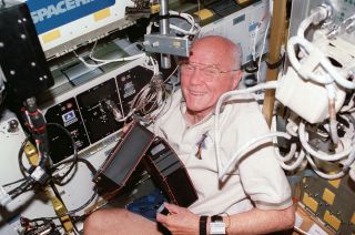 John Glenn works with an experiment inside the Spacehab module aboard space shuttle Discovery in November 1998.