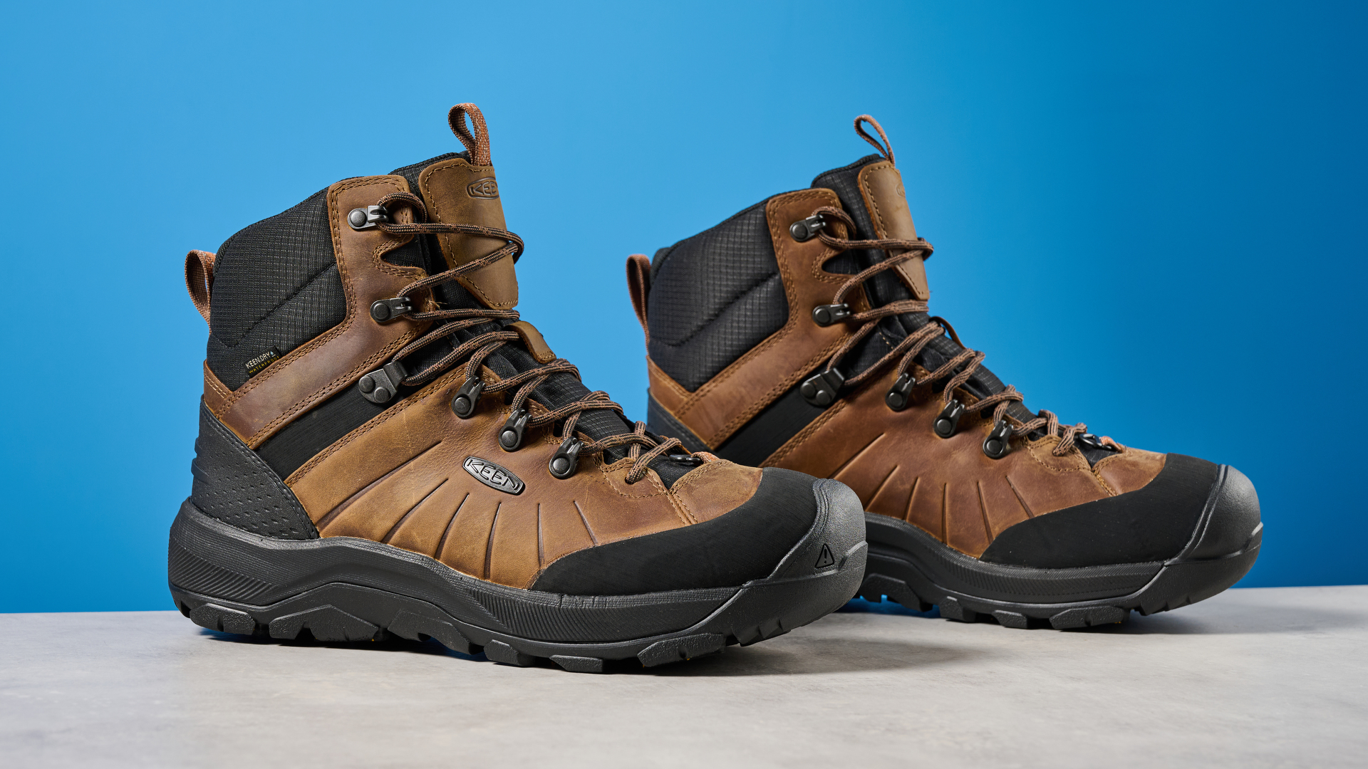 The Keen Revel IV in brown on a stone surface with a blue background