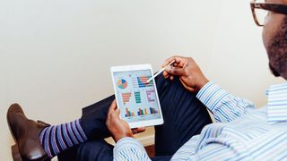 Person holding a tablet showing an analytics screen with graphs and charts