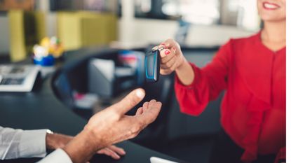 Young businesswoman in the office giving the car keys to customer