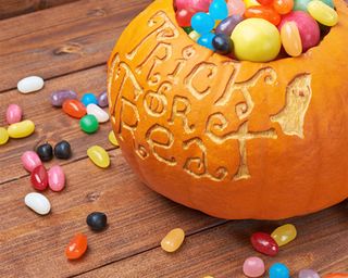A DIY Halloween decoration using carved pumpkin with assortment of candy inside cavity