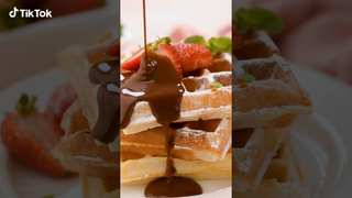 A waffle and strawberry stack being covered with chocolate sauce. This TikTok video shows how TikTok on your TV will look, with the video being used to create a background.