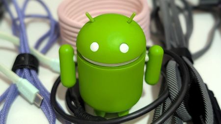 Various USB-C cables and an Android figurine on a wooden desk