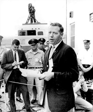 Jack King, the first chief of Public Information for NASA's Launch Operations Center at Cape Canaveral Air Force Station, briefs the news media on the May 2, 1961 postponement of the launch of Mercury Redstone-3 due to unfavorable weather. Three days later, astronaut Alan Shepard made history as the first American in space.