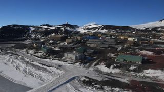a series of squat buildings on a hillside covered in snow