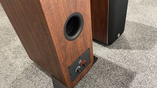 Q Acoustics M40 active floorstanding speakers on grey carpet showing rear port and binding posts