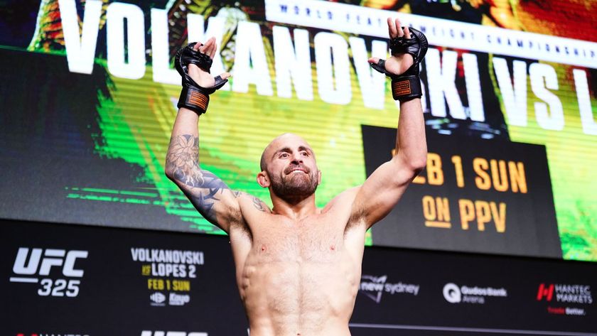 Alexander Volkanovski raises his arms to the air in the final press conference before fighting Diego Lopes in their rematch for the UFC Featherweight Championship.