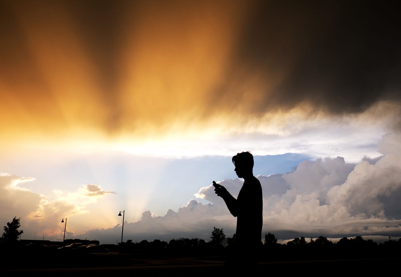 A teenager checks his cell phone.