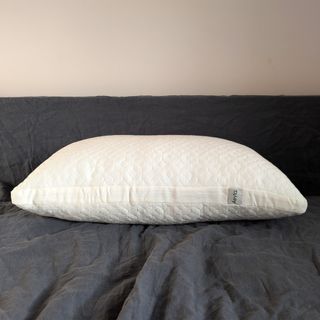 The Aeyla Adjustable FOAMO Pillow being tested on a bed with a grey linen duvet cover