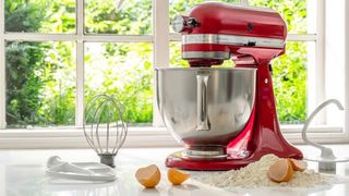 a red KitchenAid stand mixer on a counter with baking ingredients around it