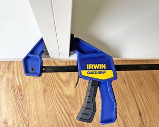 A clamp holding two kitchen cabinets together during installation