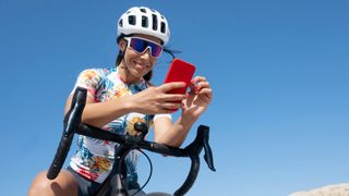 Woman looking at phone, sitting on bicycle with phone mount