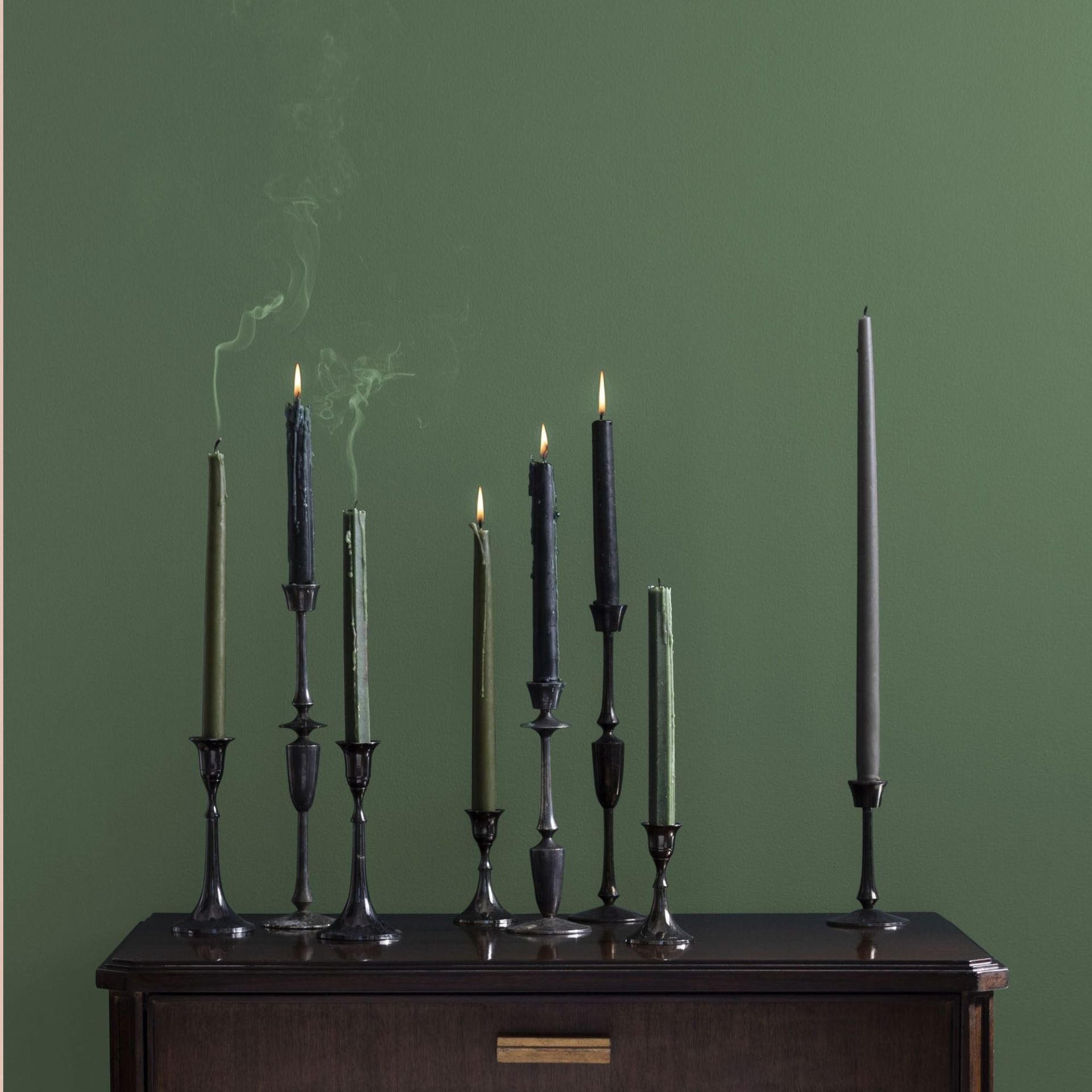 A green wall with a table and candles in front