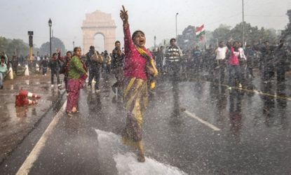 A protester chants as she braces herself against water fired from police cannons during a demonstration against the gang-rape of a young woman.