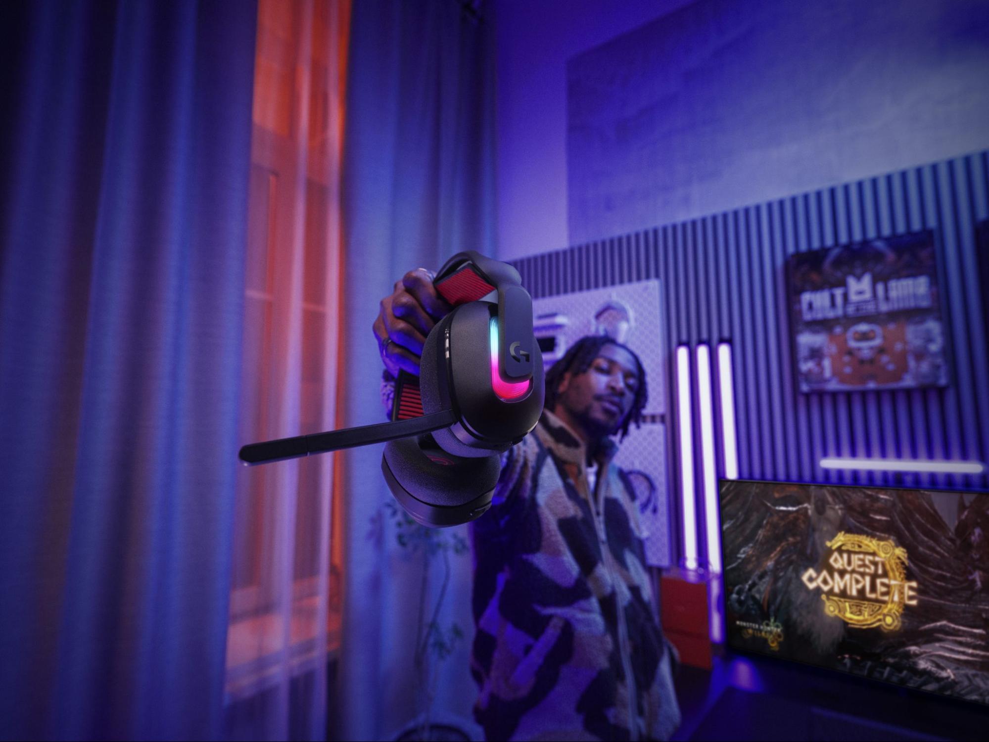 Gamer holding the Logitech G Astro A20 X Lightspeed Wireless Gaming Headset in a living room.