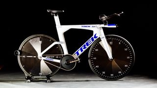 A white track TT bike with two disc wheels with clock motif decals