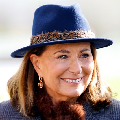 Carole Middleton wearing a blue feathered fedora and smiling