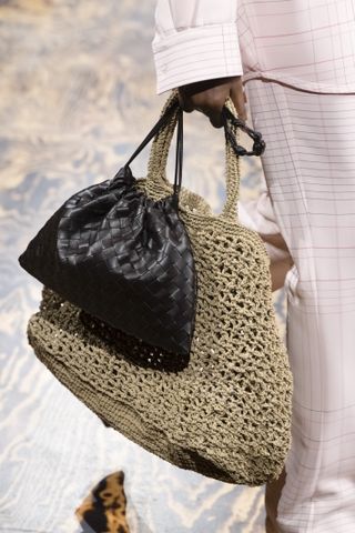 a model carrying two bottega veneta bags on the runway to illustrate the double bag trend