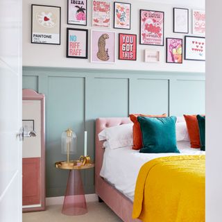 Bedroom with mint coloured panelling and pink art on a gallery wall