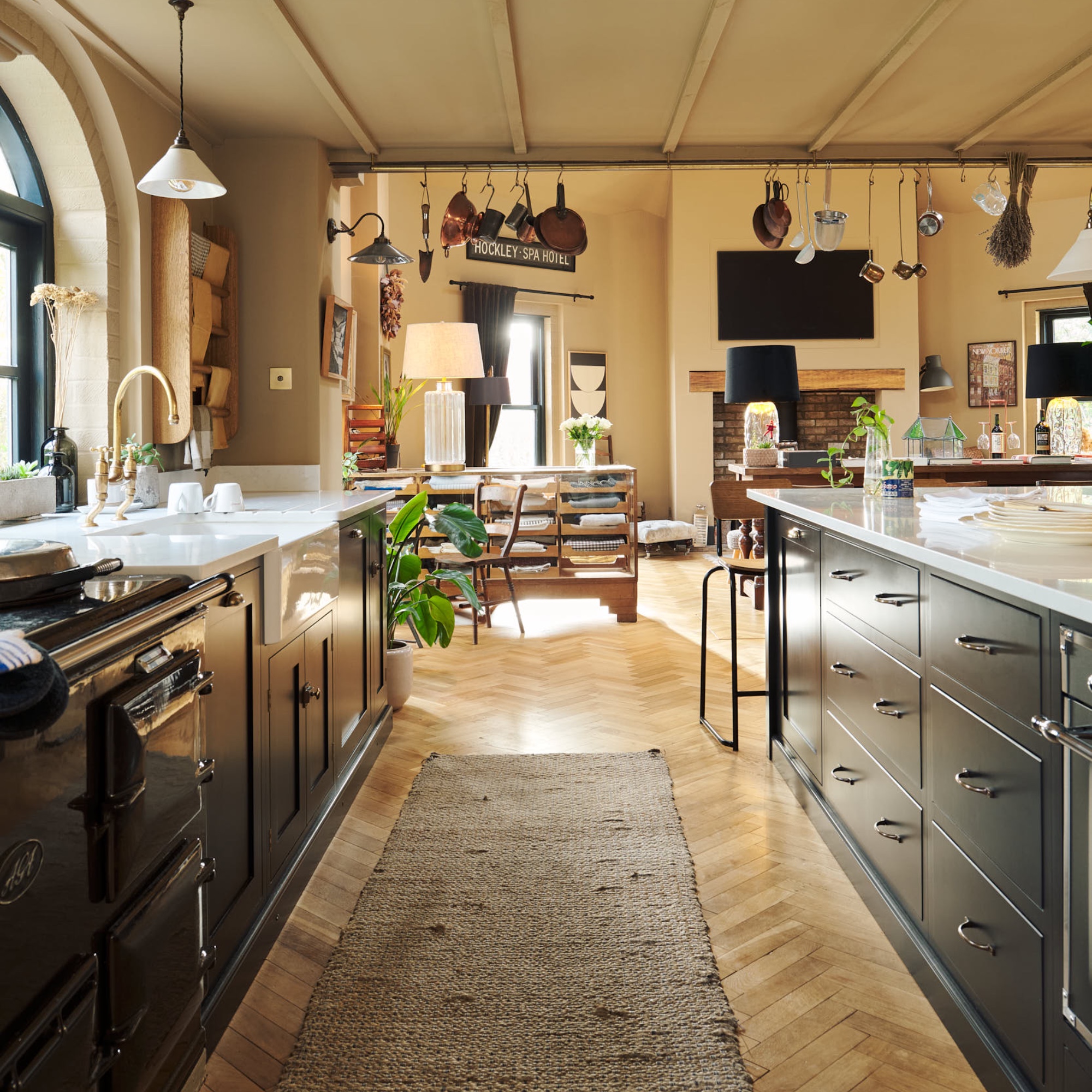 black kitchen with parquet flooring, ochre walls, white worktops, open plan living space