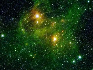 Two extremely bright stars illuminate a greenish mist in this image from the Spitzer Space Telescope's