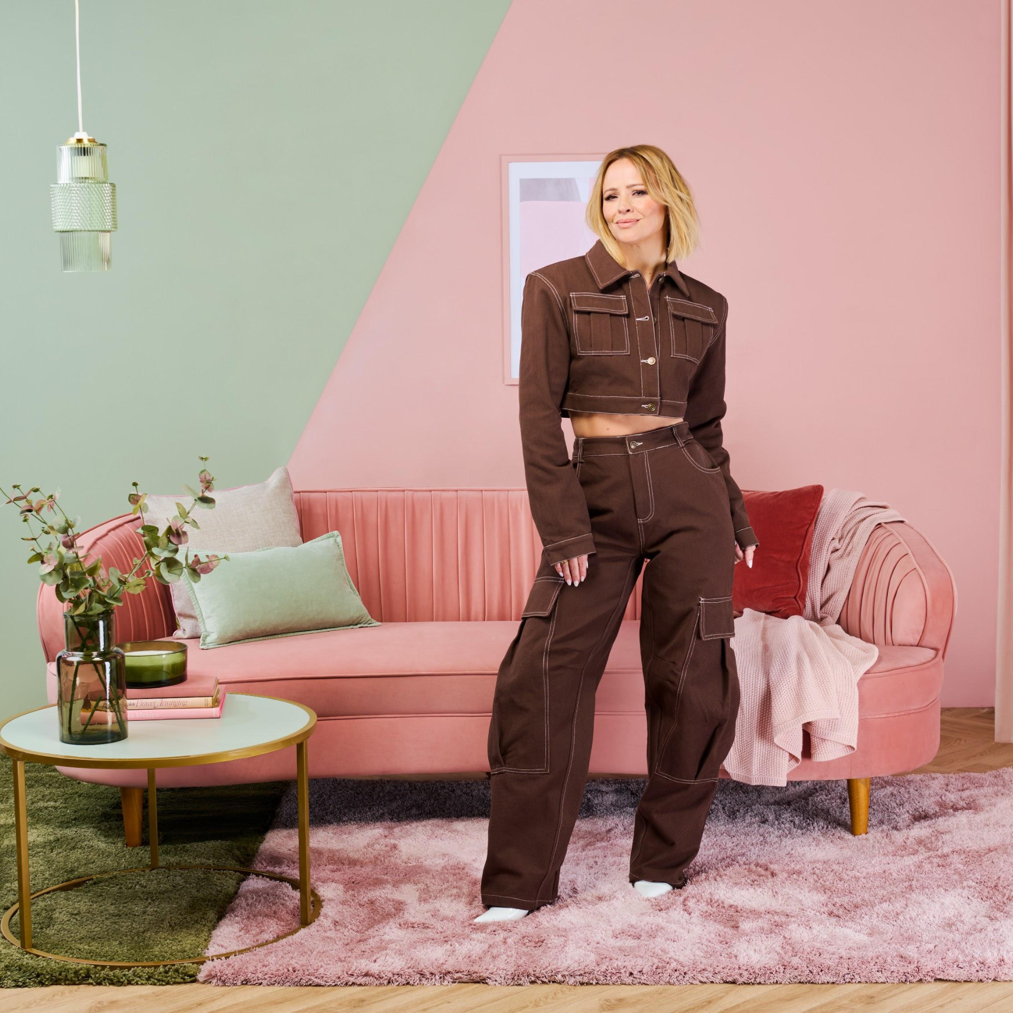 Kimberley Walsh posing in a pink and green living room, painted in the colours subtle sage and blush rose.