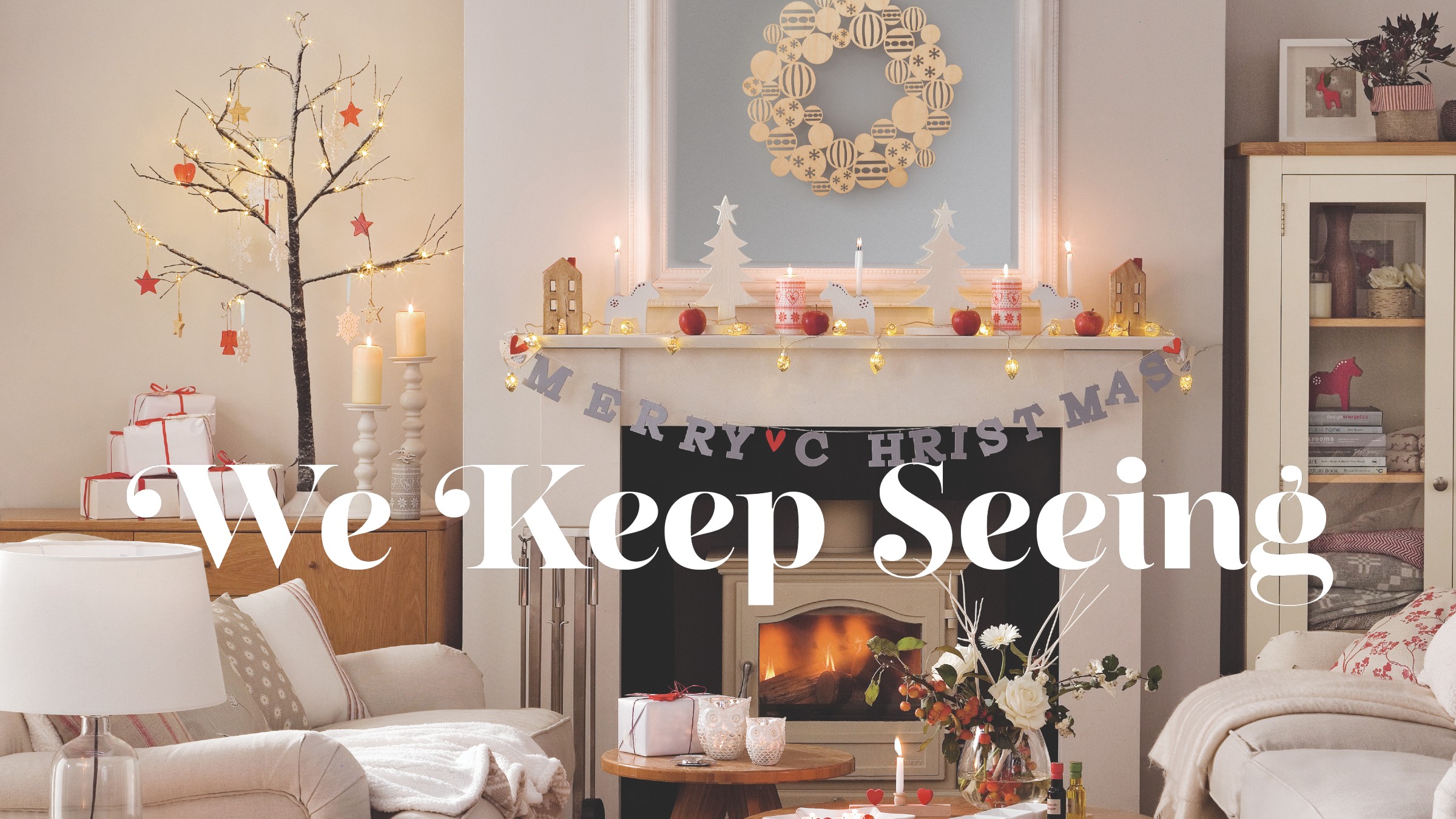 A white living room decorated for Christmas with a small tabletop twig Christmas tree decorated with red star ornaments set up on a sideboard