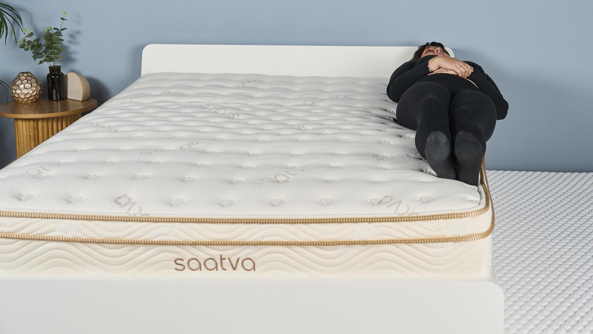 Mattress tester Lauren Jeffries lies on the Saatva Classic mattress, dangling over the edge of the bed.