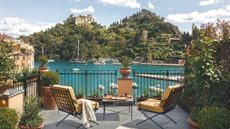A view from a suite terrace over two verdant green hills overlooking a cerulean sea in the Bay of Portofino