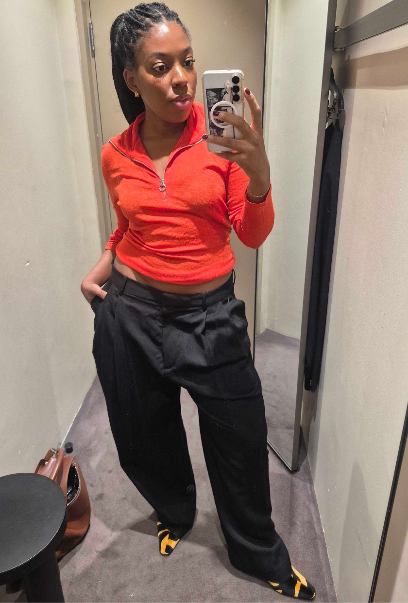 An image of Who What Wear UK fashion editor Remy Farrell wearing the COS Relaxed Fluid Wide-leg Trousers with a red half-zip polo and tiger-print boots.