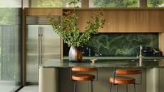 a wood kitchen with a green stone countertop and a stainless steel fridge