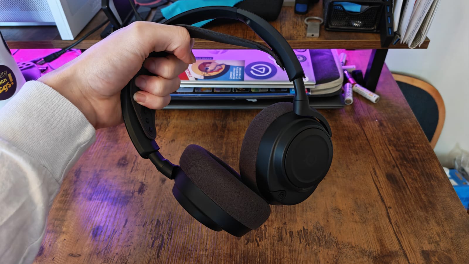 A reviewer holding the SteelSeries Arctis Nova 7 Gen 2