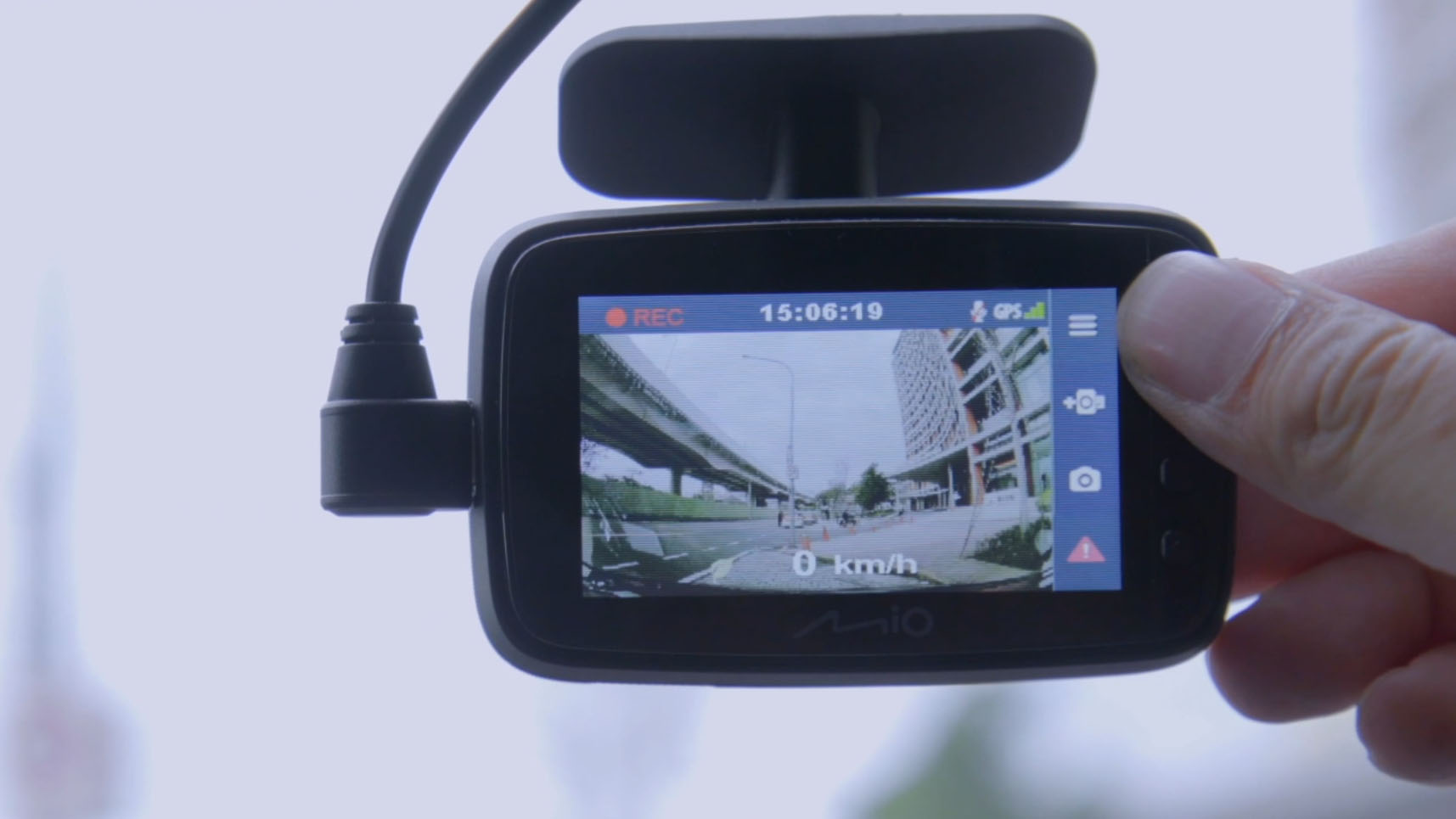 A hand holding the Mio Mivue 818 dash cam on a windshield