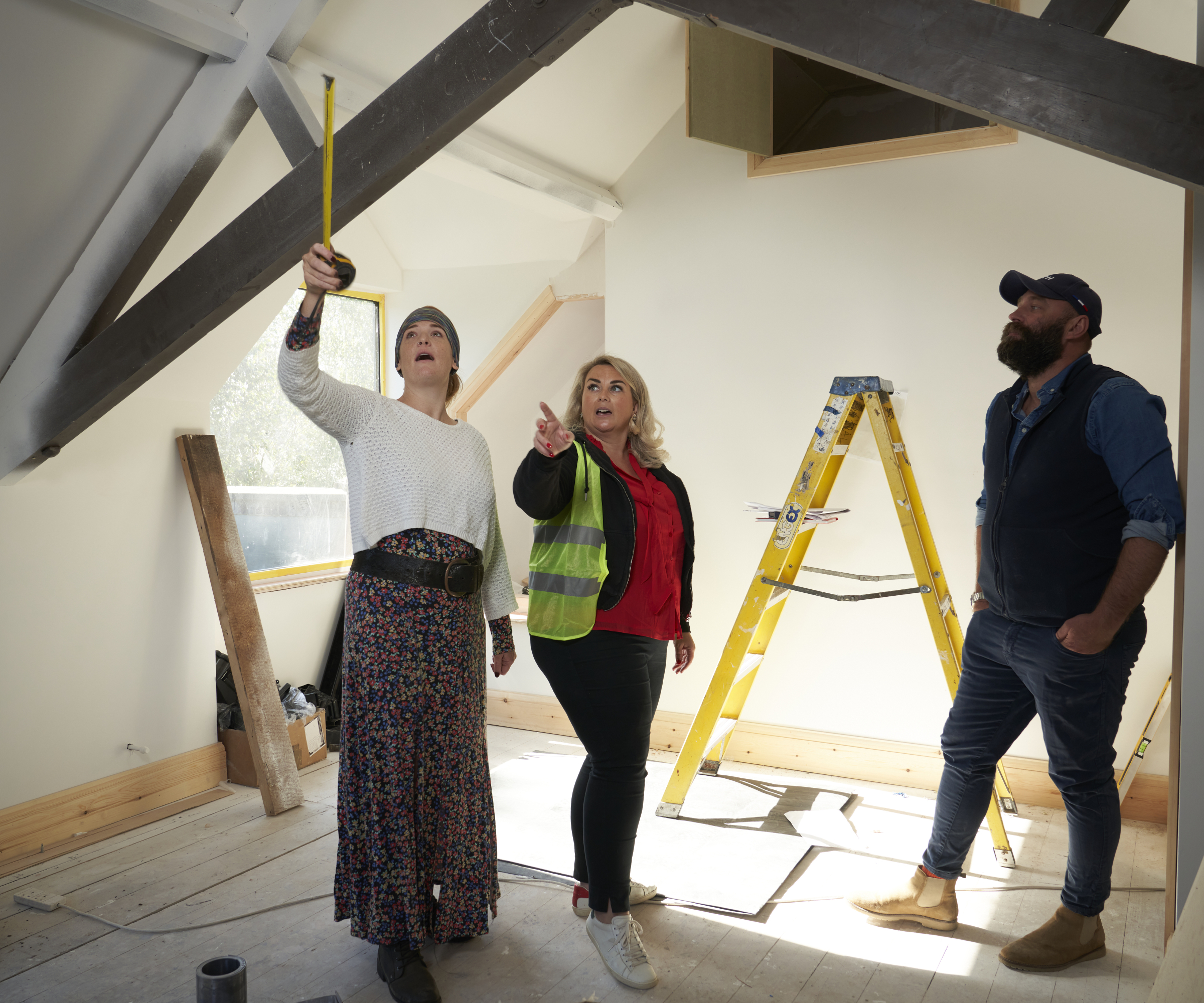 two females and male stood in loft looking at roof beams