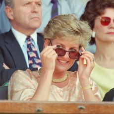 Princess Diana pulling down her sunglasses in a peach top at Wimbledon