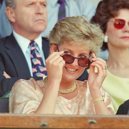 Princess Diana pulling down her sunglasses in a peach top at Wimbledon