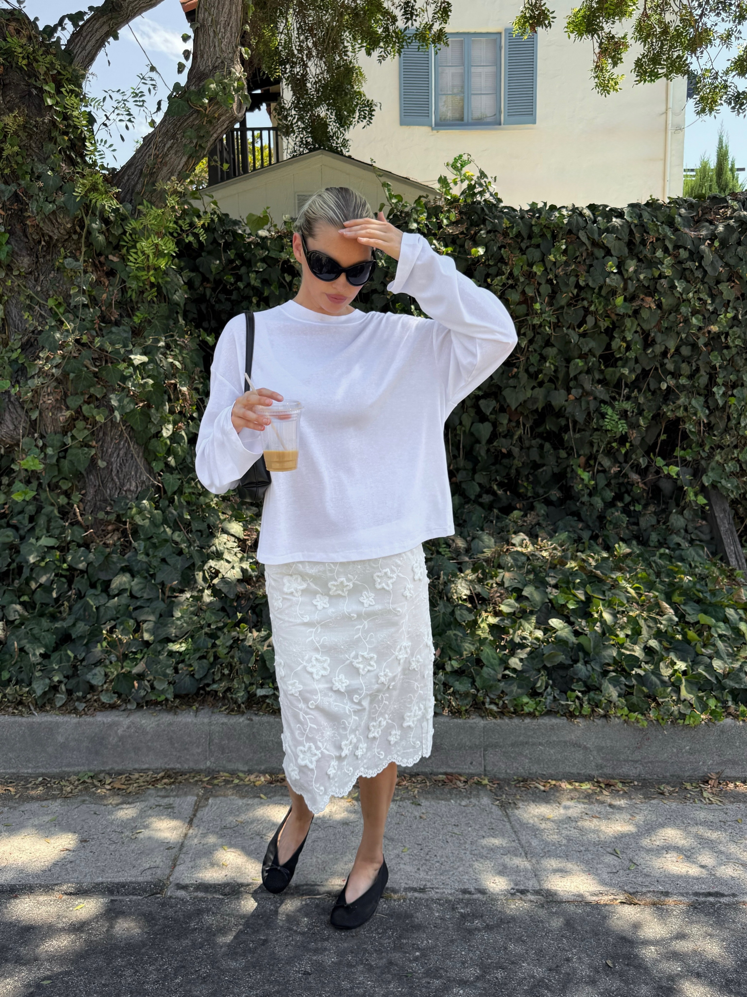 Model @hoskelsa wears a baggy long-sleeve t-shirt with a knee-length skirt and ballet pumps.