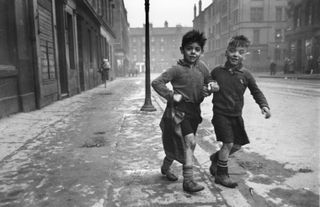 Black and white photo of two boys walking through the streets of Glasgow.
