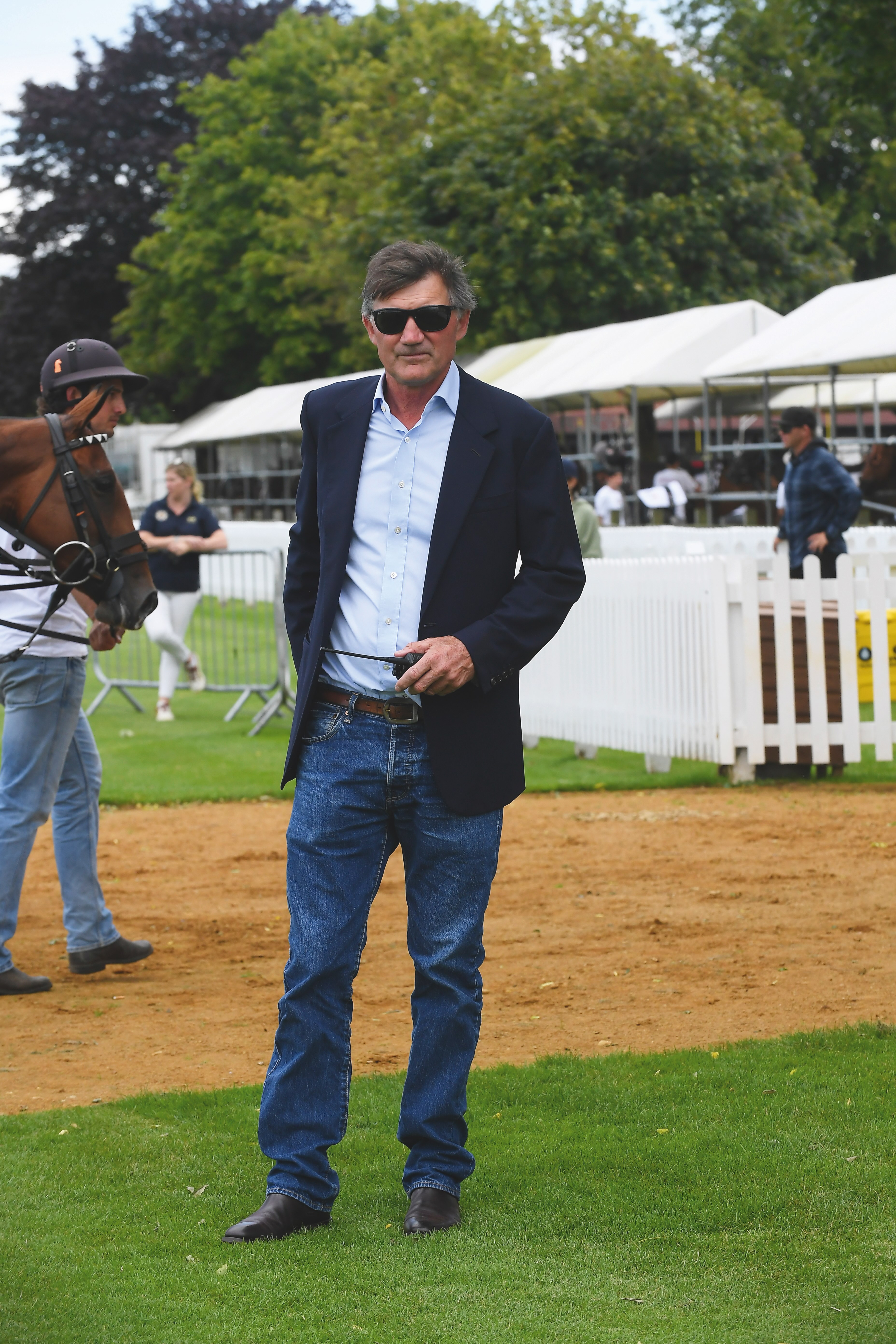 Antony Fanshawe stands on the lawn at Guards Polo club in some blue jeans, a blazer and some sweet shades
