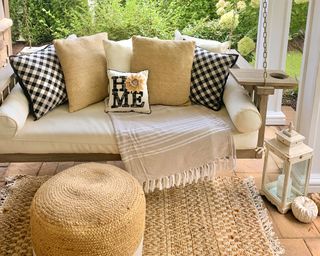 Porch with cushions throws blankets rug lantern and ottoman - rusticglamdup
