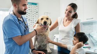 Family petting dog while vet examines him